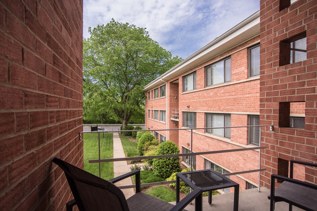 a balcony with a table and chairs in front of a brick building