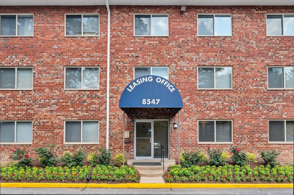 a brick building with a blue awning and the words leasing office on it