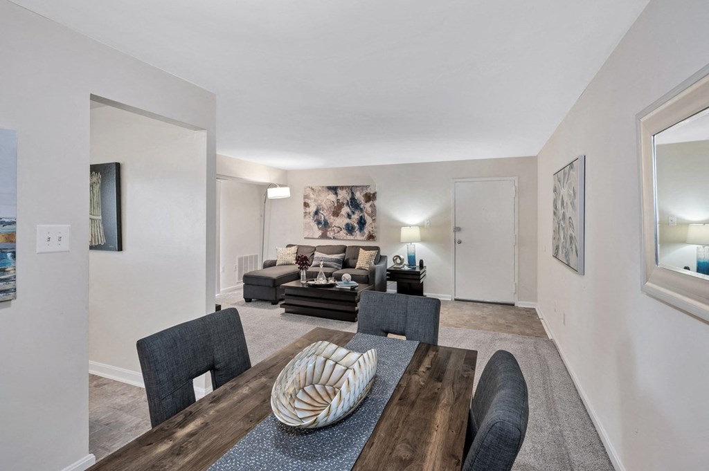 a living room with white walls and a wooden table and chairs