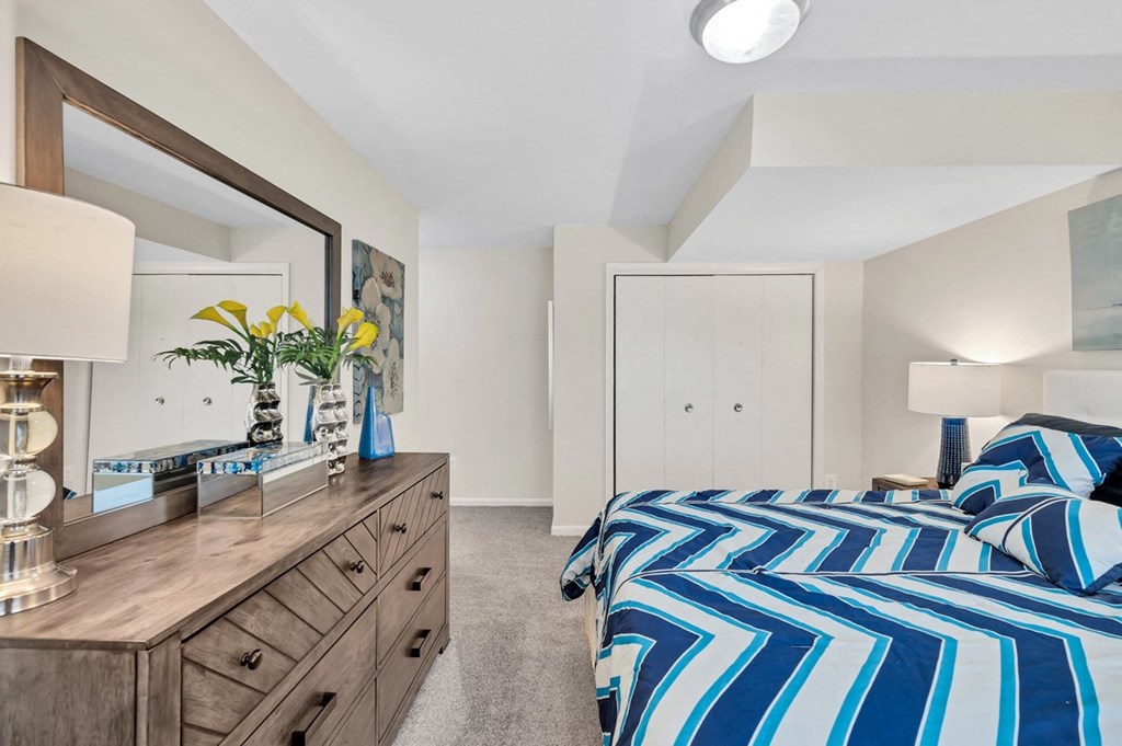 a bedroom with a bed and a dresser with a mirror