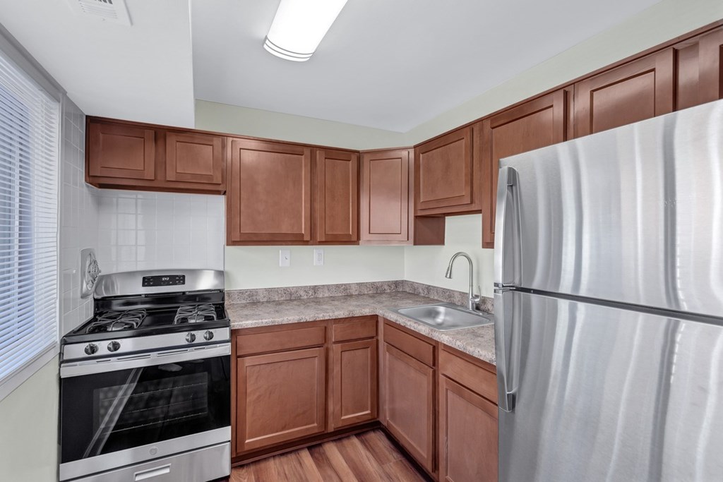 A kitchen with brown cabinets and a stainless steel refrigerator.