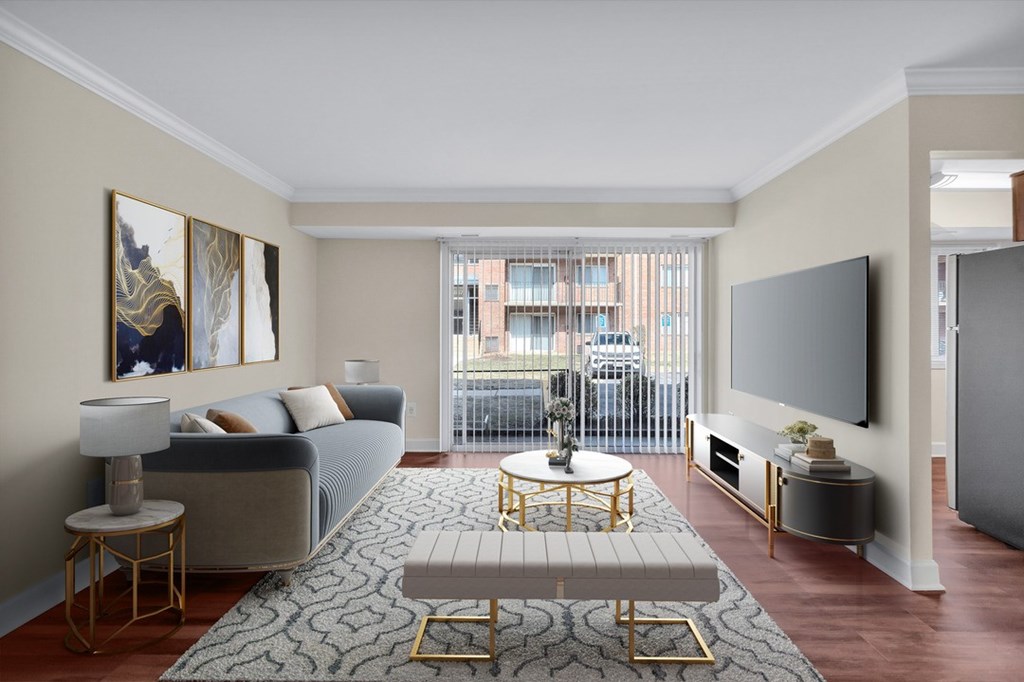 A living room with a grey couch, a round gold coffee table, and a large painting on the wall.