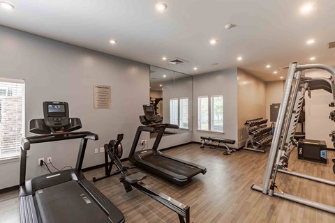 A spacious gym with treadmills, elliptical machines, and a weight rack.