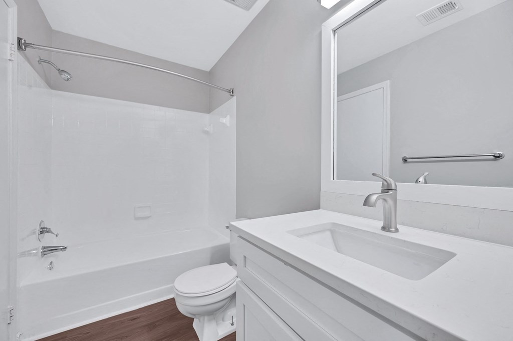 A minimalist white bathroom, complete with a sink, toilet, and shower, epitomizing elegance and functionality.