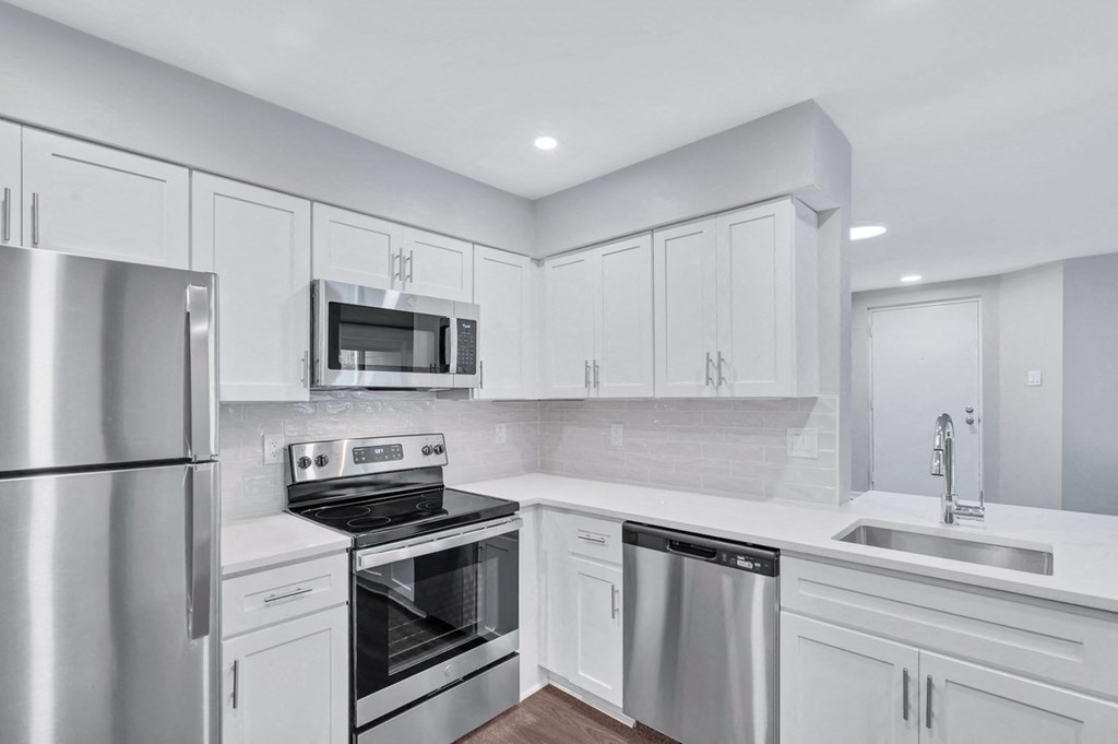 Immaculate kitchen featuring sleek stainless steel appliances and pristine white cabinets.