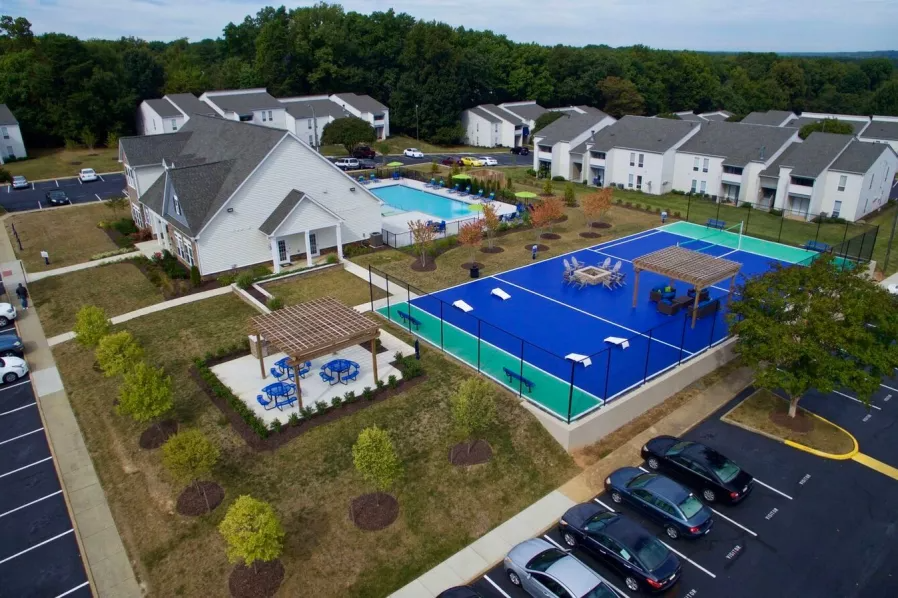 an aerial view of a large tennis court and a parking lot with houses and cars