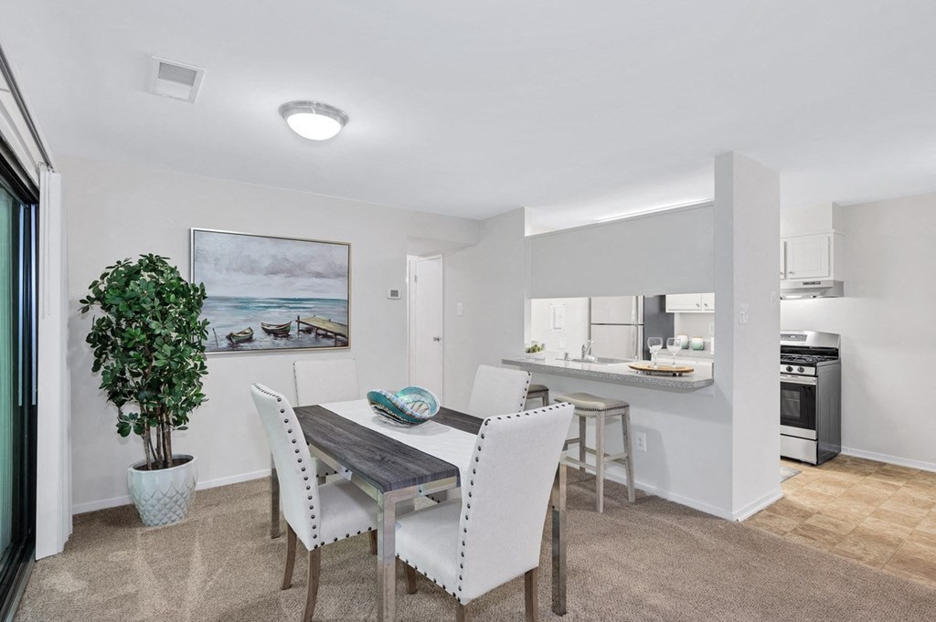 a dining area with a table and chairs and a kitchen in the background