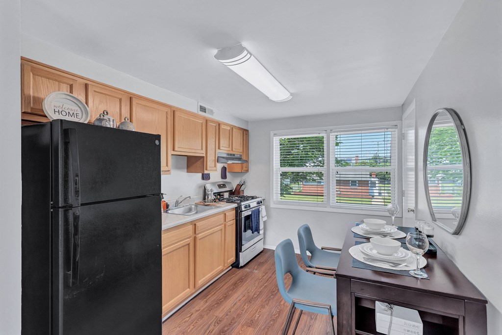 a kitchen with a black refrigerator and a table and chairs