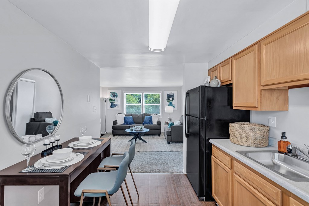 a kitchen and living room with a black refrigerator and a table with chairs