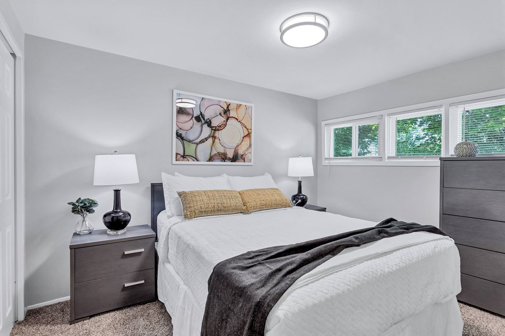 a bedroom with a white bed and two windows