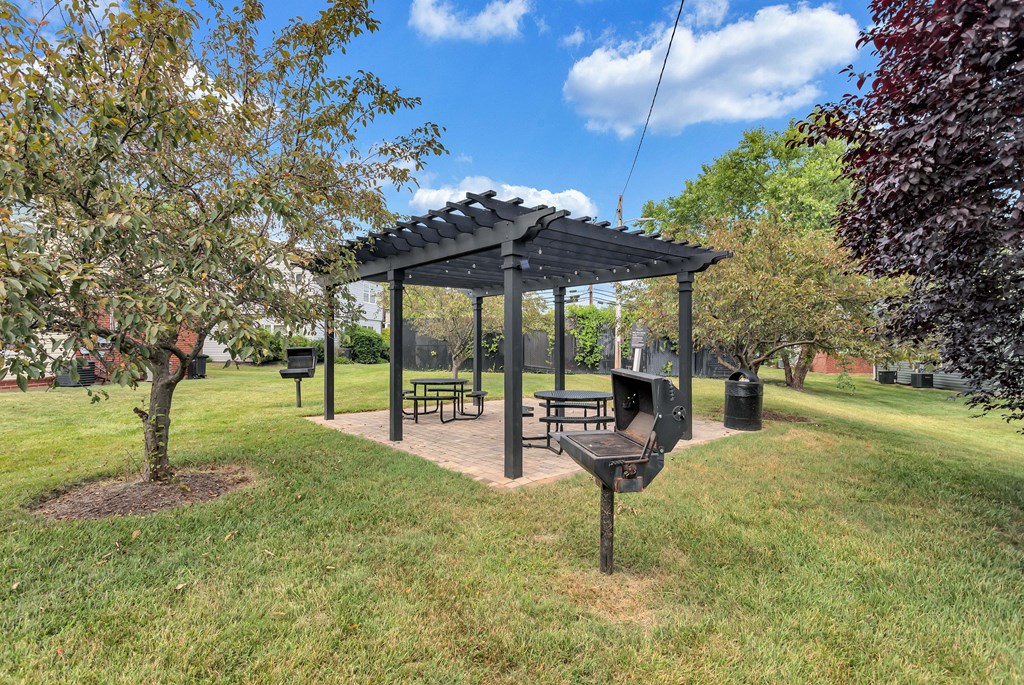a picnic area with a grill and a pavilion in a park
