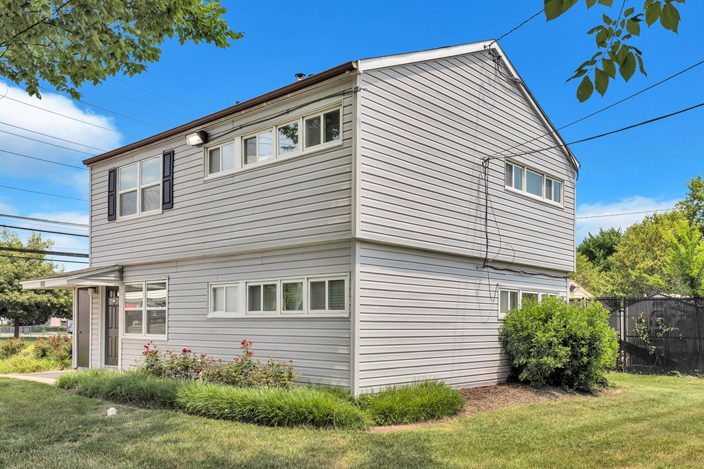 the back of a gray house with white siding and a yard with grass
