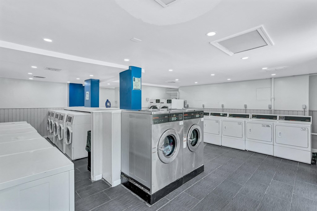 a large laundry room with washers and dryers and a row of washing machines