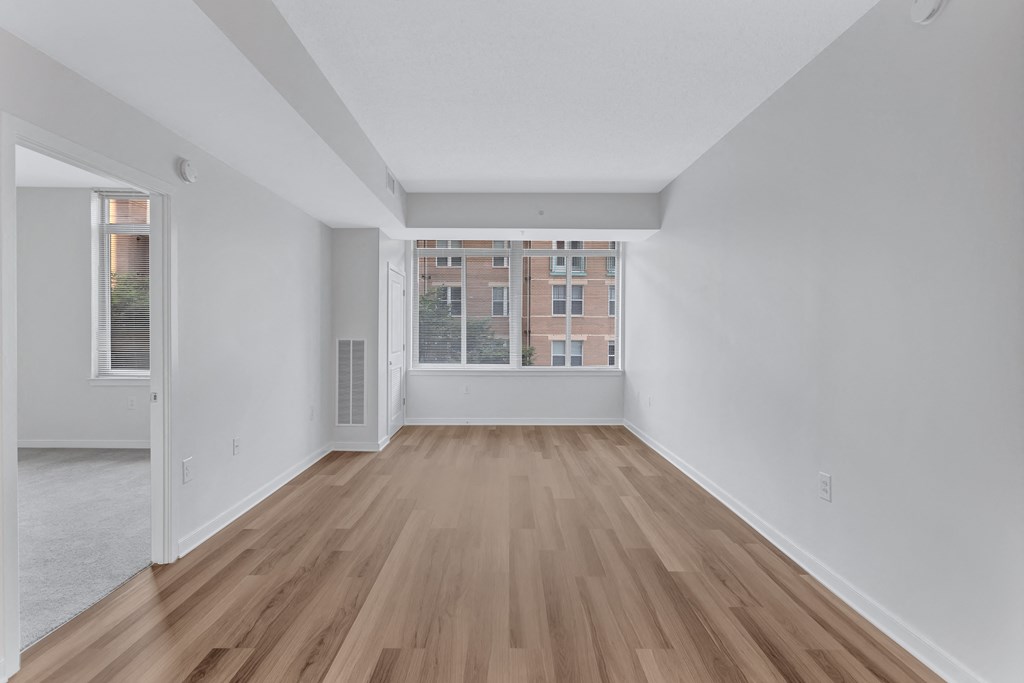 a spacious living room with hardwood floors and a large window