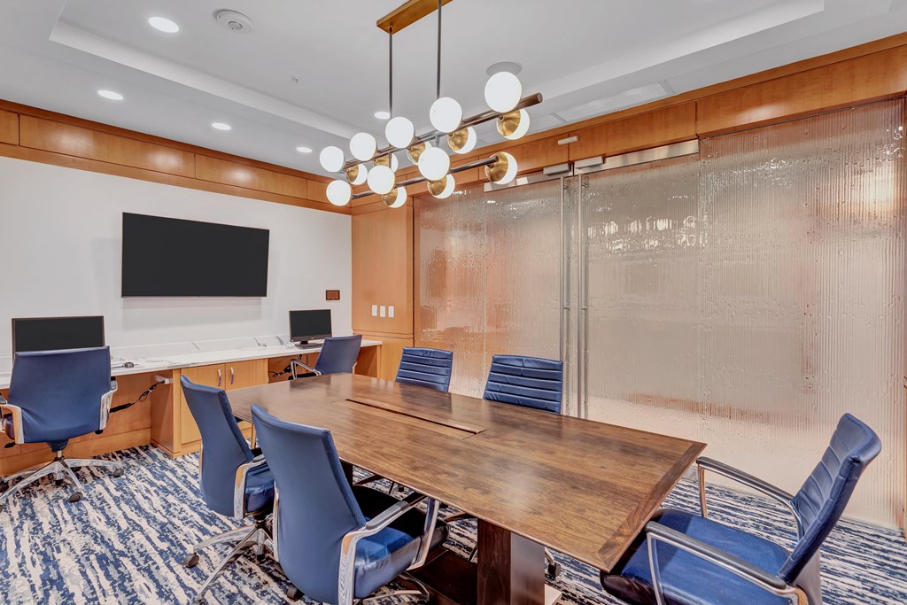 a conference room with a long wooden table and chairs and a monitor on the wall
