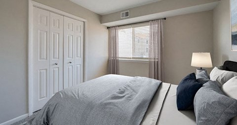 A bedroom with a large bed and a window with curtains.