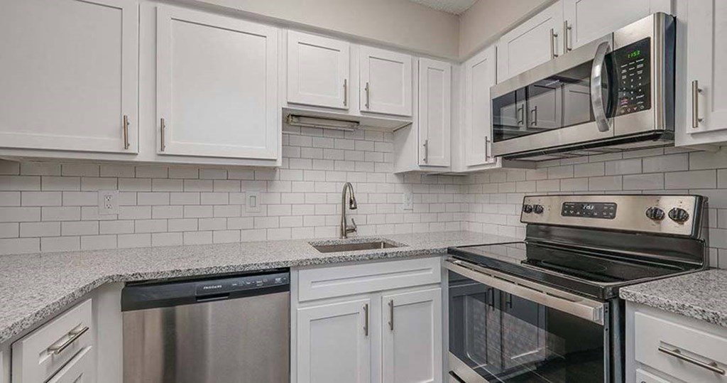 a kitchen with white cabinets and a stove and a microwave