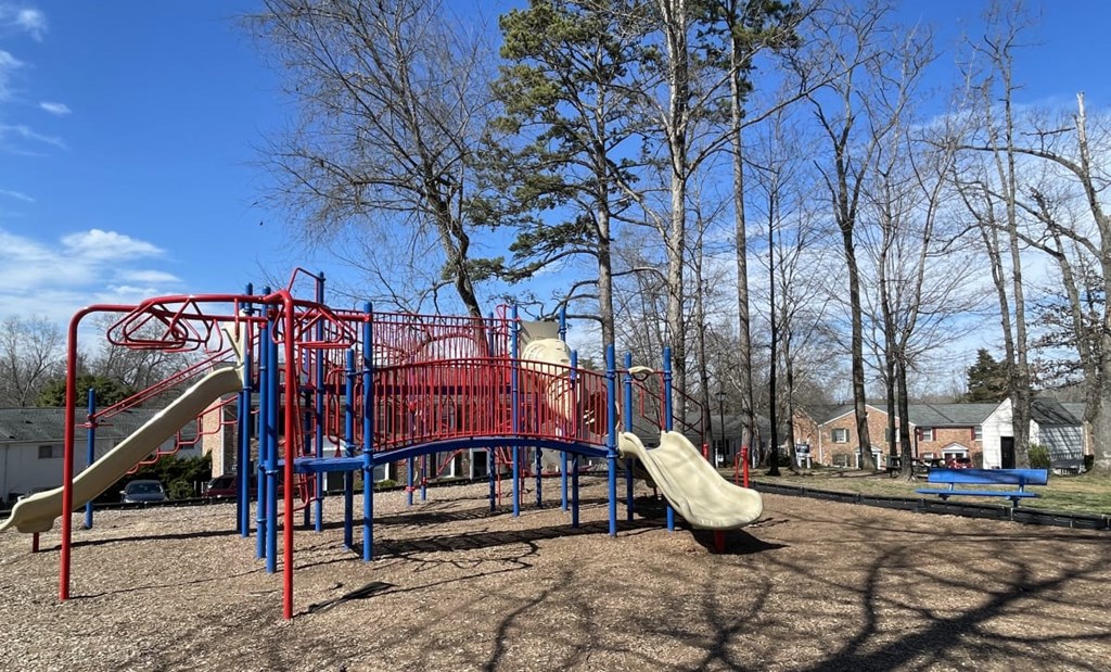 A playground with a red and blue structure and a yellow slide.