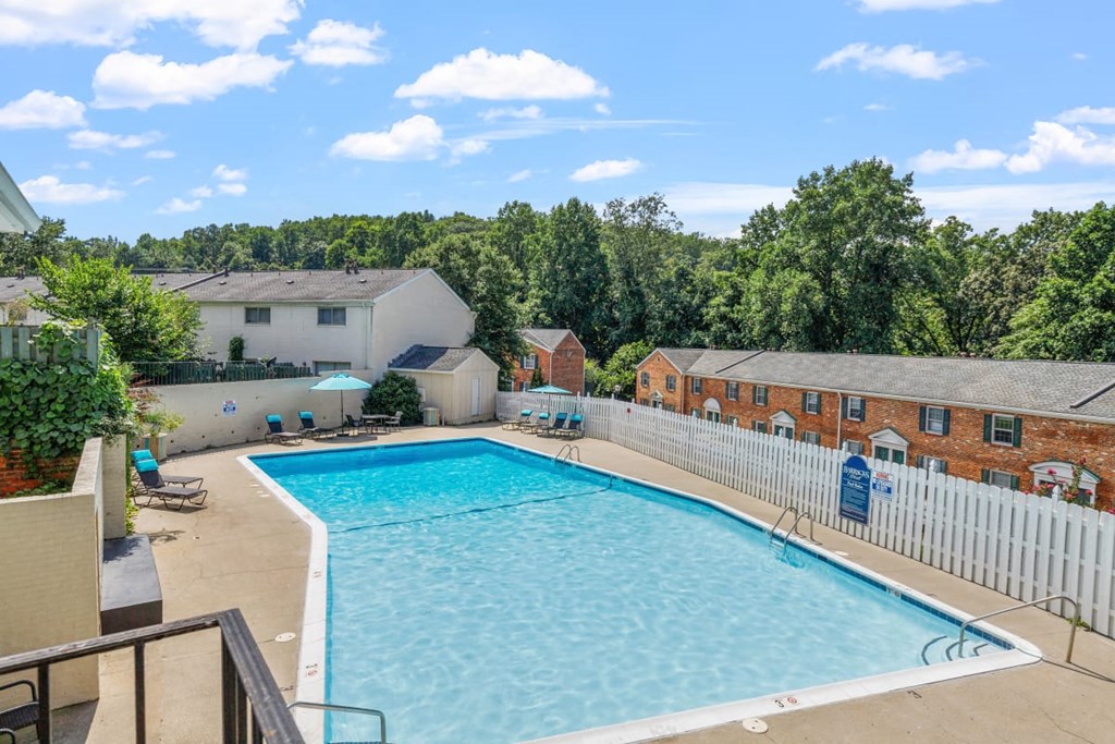 A large swimming pool in a backyard surrounded by a white fence.