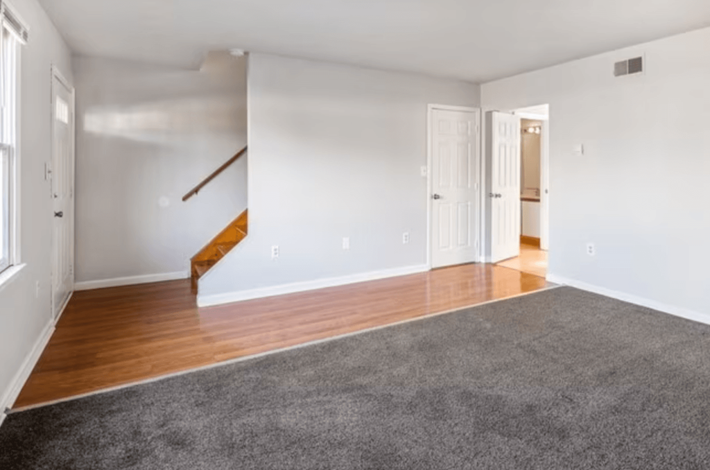 an empty living room with wood flooring and white walls