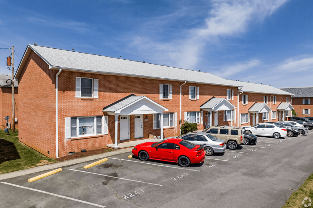 a parking lot in front of a brick building with cars parked in front