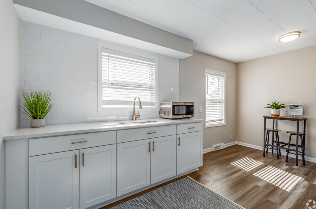 a kitchen with white cabinets and a sink and a microwave