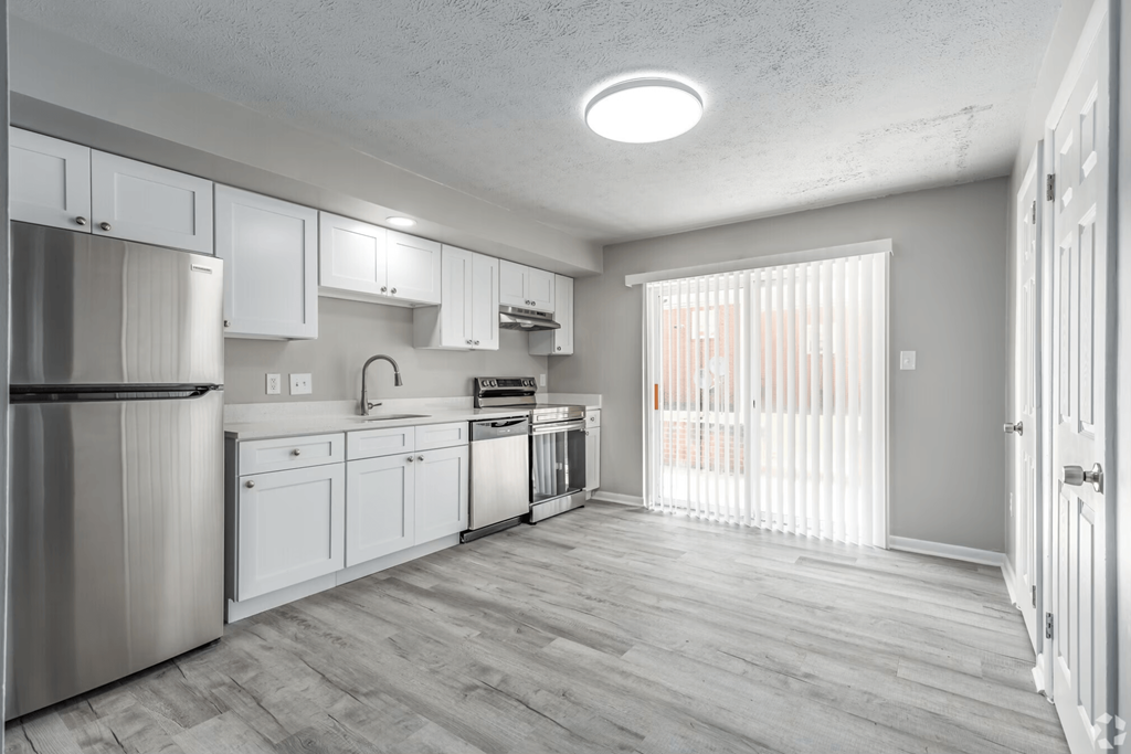 an empty kitchen with white cabinets and stainless steel appliances