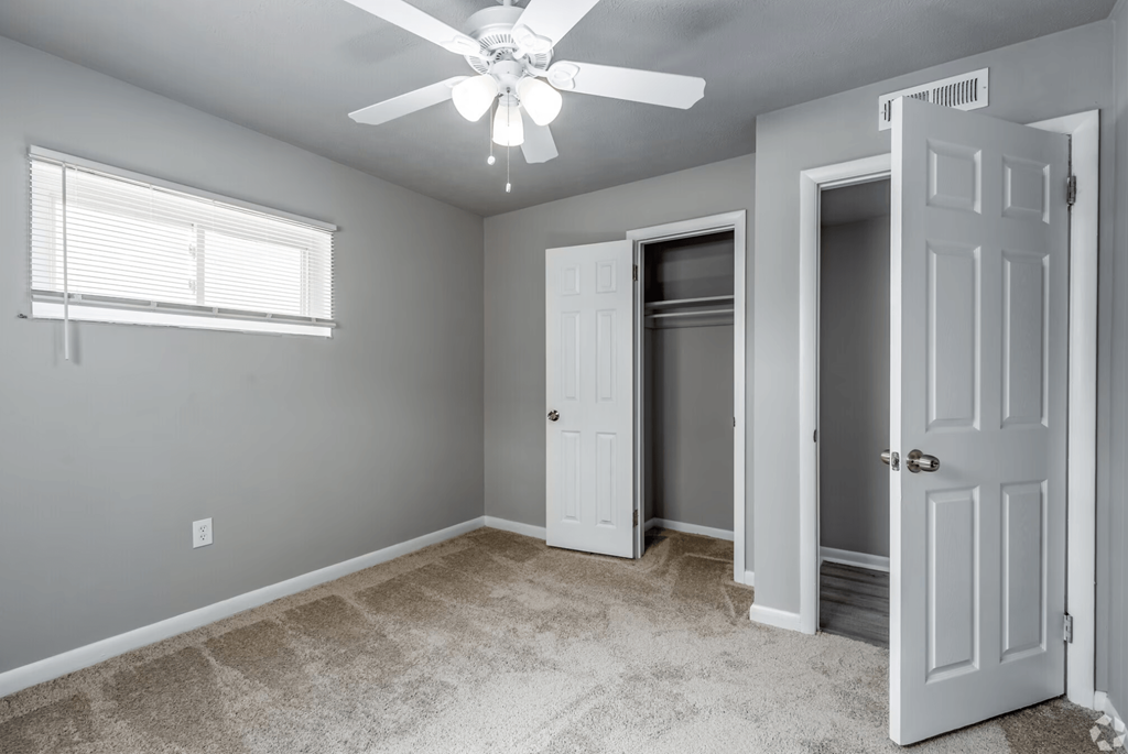 a bedroom with gray walls and a ceiling fan and a closet