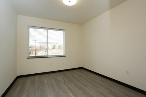 an empty room with a window and wood floors