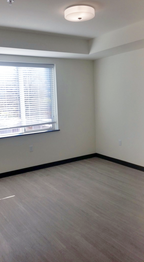 an empty room with a window and wood floors