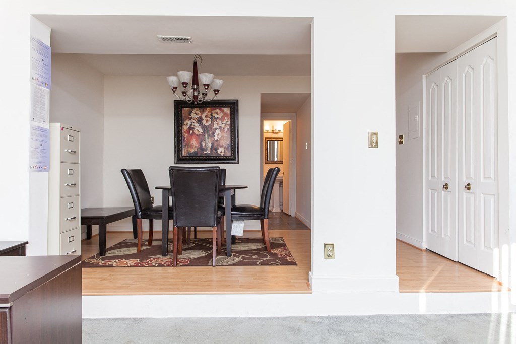 a dining room with a table and chairs and a hallway with a white door