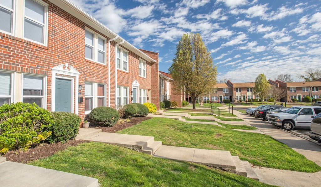 A row of red brick houses with green lawns in front.