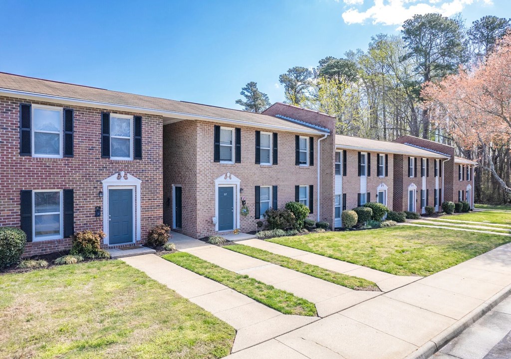 A row of red brick houses with green lawns in front.