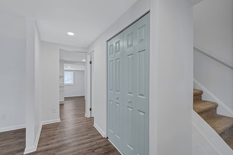 A hallway with a blue door and wooden floors.