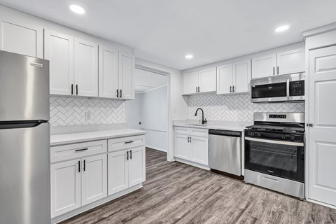 A modern kitchen with white cabinets and stainless steel appliances.