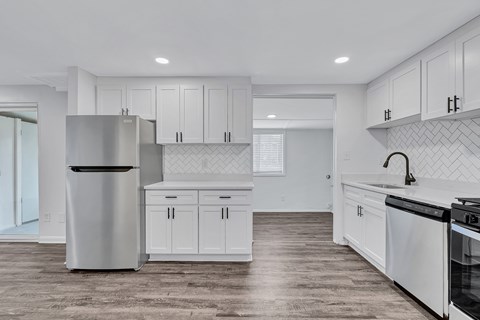 A modern kitchen with white cabinets and a wooden floor.