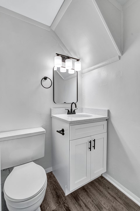 A white toilet sits next to a white sink in a small bathroom.