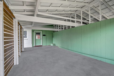 A long hallway with a green wall and a door at the end.