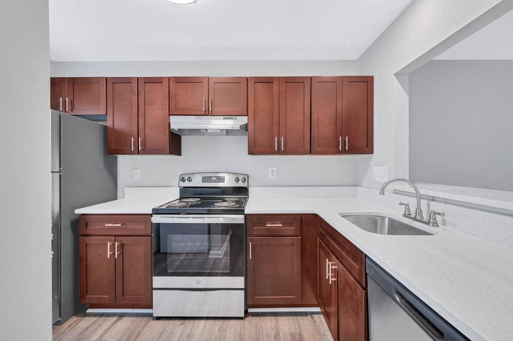 a kitchen with white countertops and dark wood cabinets