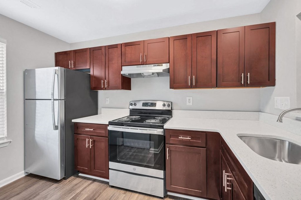 a kitchen with dark wood cabinets and white countertops