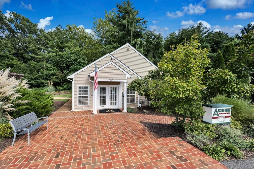 a small white house with a brick driveway and an flag