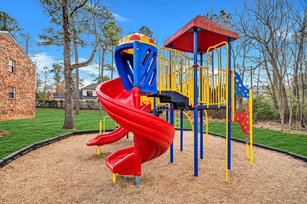 a playground with a red slide and blue and yellow equipment