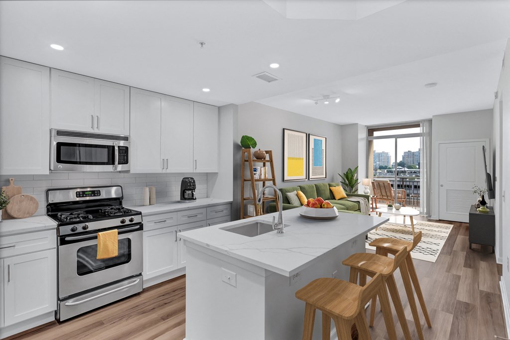an open kitchen and living room with white cabinets and a marble counter top
