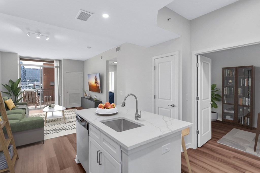 an open kitchen and living room with a white counter top and a sink