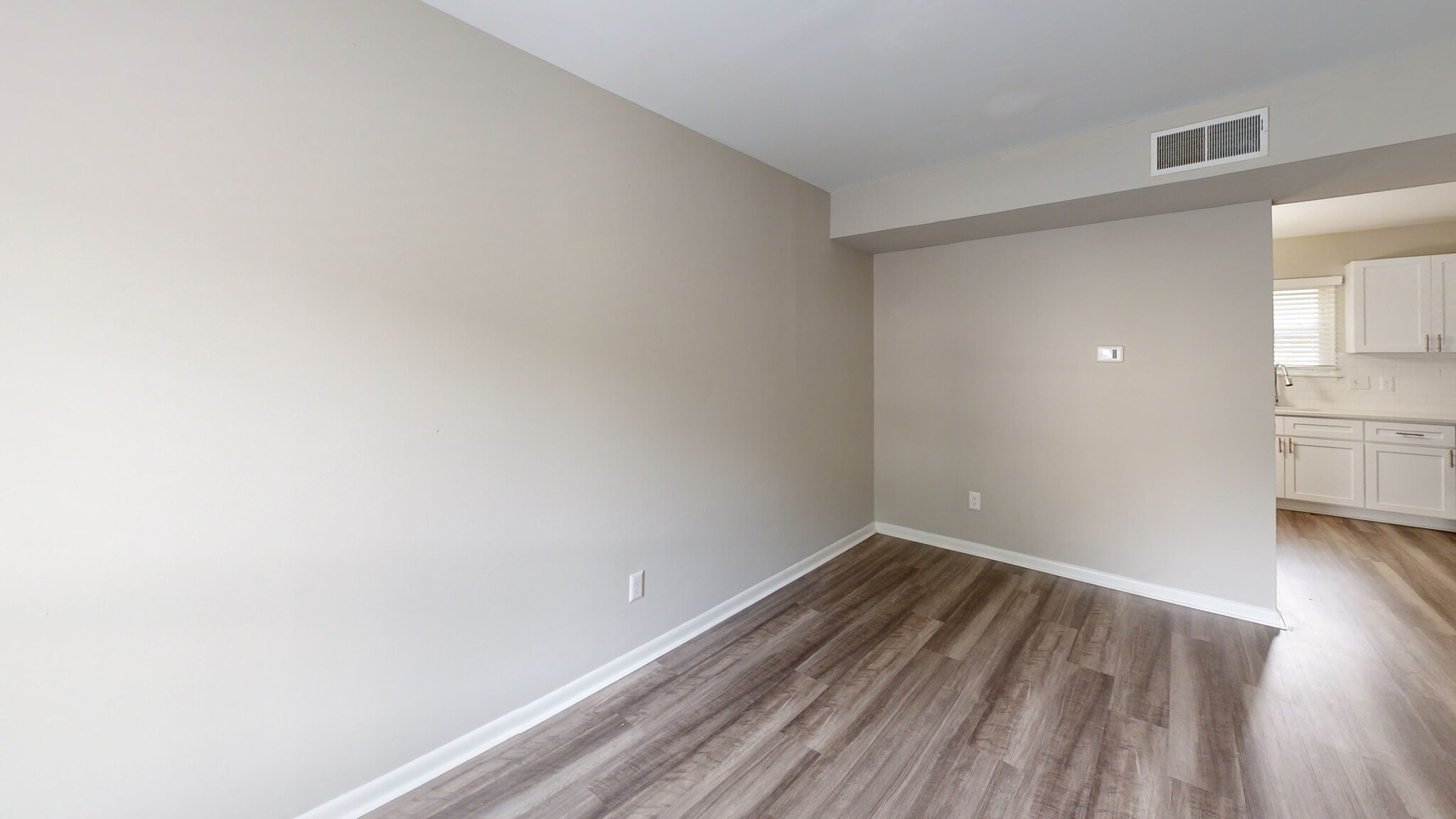 an empty room with white walls and wood flooring
