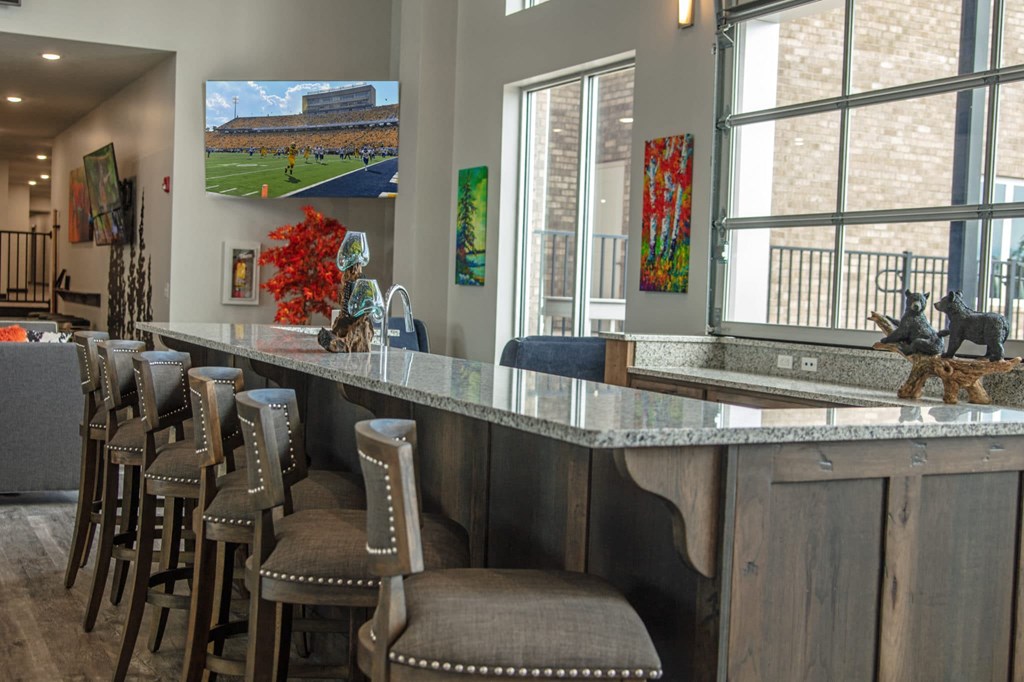 a bar with stools in a living room with large windows