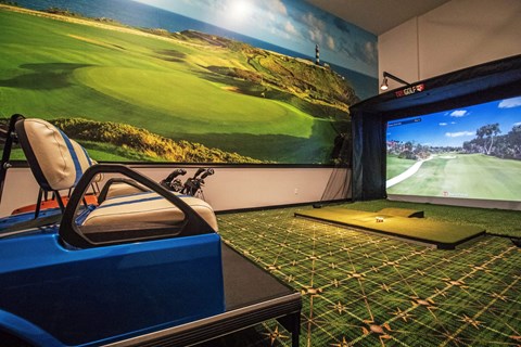 a game room with a golf simulator and a large screen tv