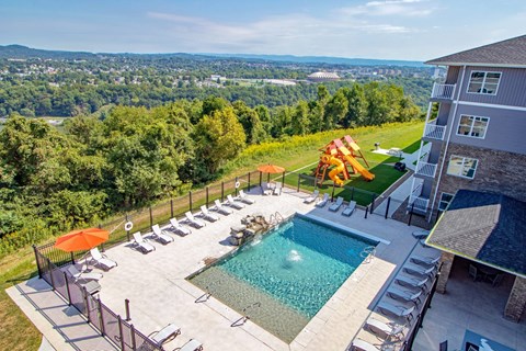 a swimming pool with chairs and umbrellas in front of a house