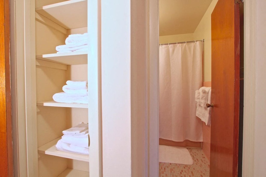 a bathroom with a white shower curtain and a white towel on a white shelf
