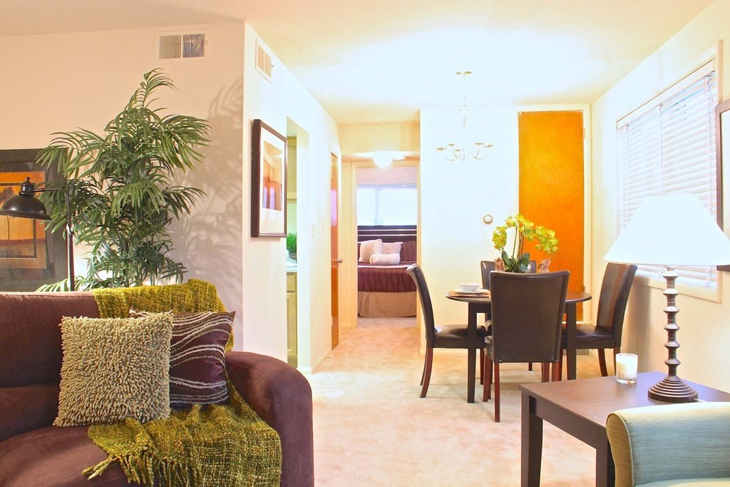 a living room with a couch and a chair and a dining room table in the background